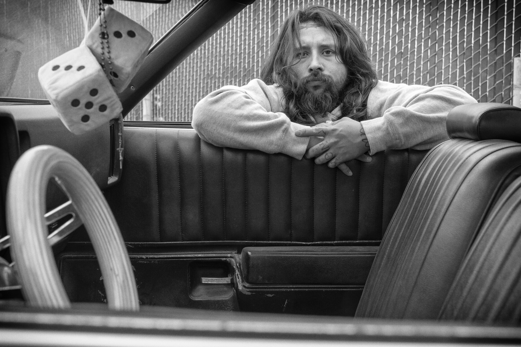 Mark Hocutt looking at the viewer through a window of his ‘73 Chevy El Camino, “Electric Funeral”