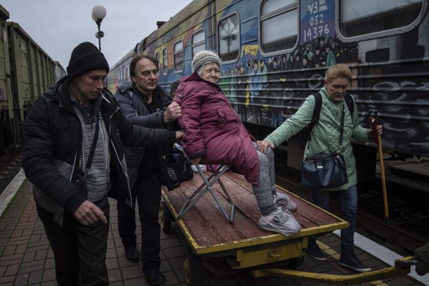 Relatives of Elizaveta, 94, transport her by a cargo cart to the evacuation train in Kherson, Ukraine, Thursday, Dec. 1, 2022. (AP Photo/Evgeniy Maloletka)