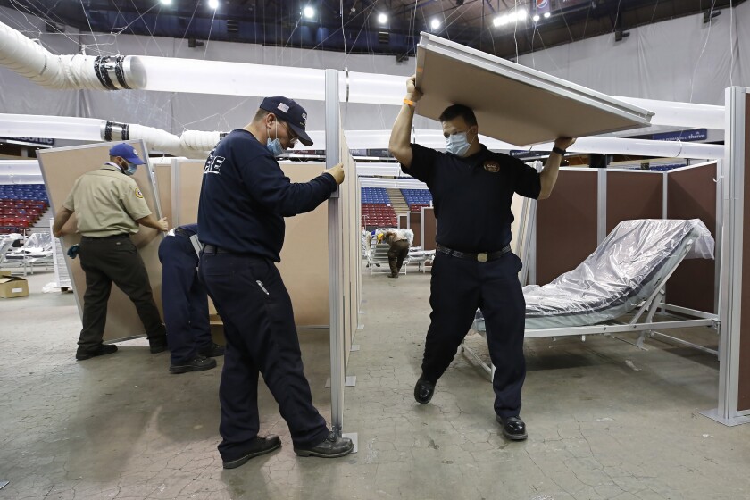 FILE — In this April 18, 2020 file photo partitions are installed between beds as work is performed to turn Sleep Train Arena into a 400-bed emergency field hospital to help deal with the coronavirus, in Sacramento, Calif. The state has reopened the arena and other facilities to help handle a new surge of coronavirus patients, but is using little more than a handful of volunteers from Gov. Gavin Newsom's California Health Corps who originally helped staff the facility. (AP Photo/Rich Pedroncelli, File)
