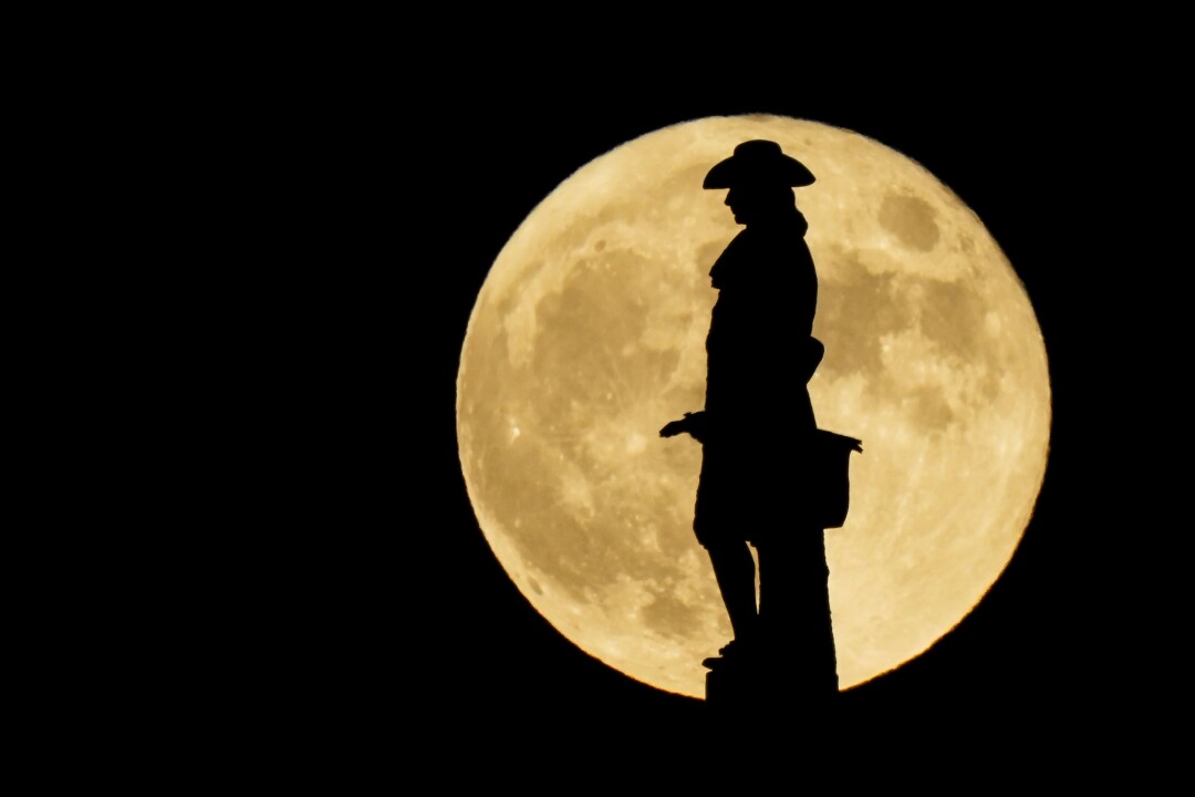 Philadelphia's statue of William Penn is silhouetted against the full moon