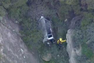 A firefighter inspects a vehicle that went over the side of a canyon in Malibu on Wednesday, April 3, 2024.