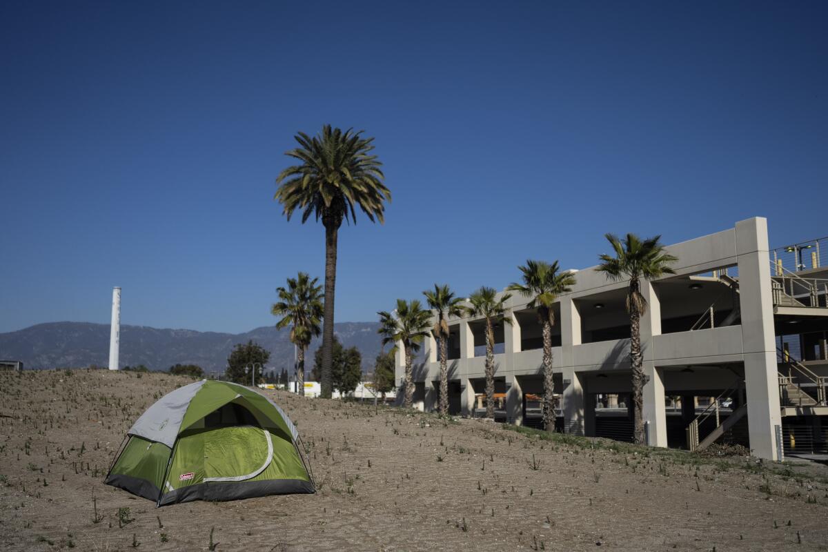 Una casa de campaña de un indigente junto a una estructura vacía en San Bernardino, California
