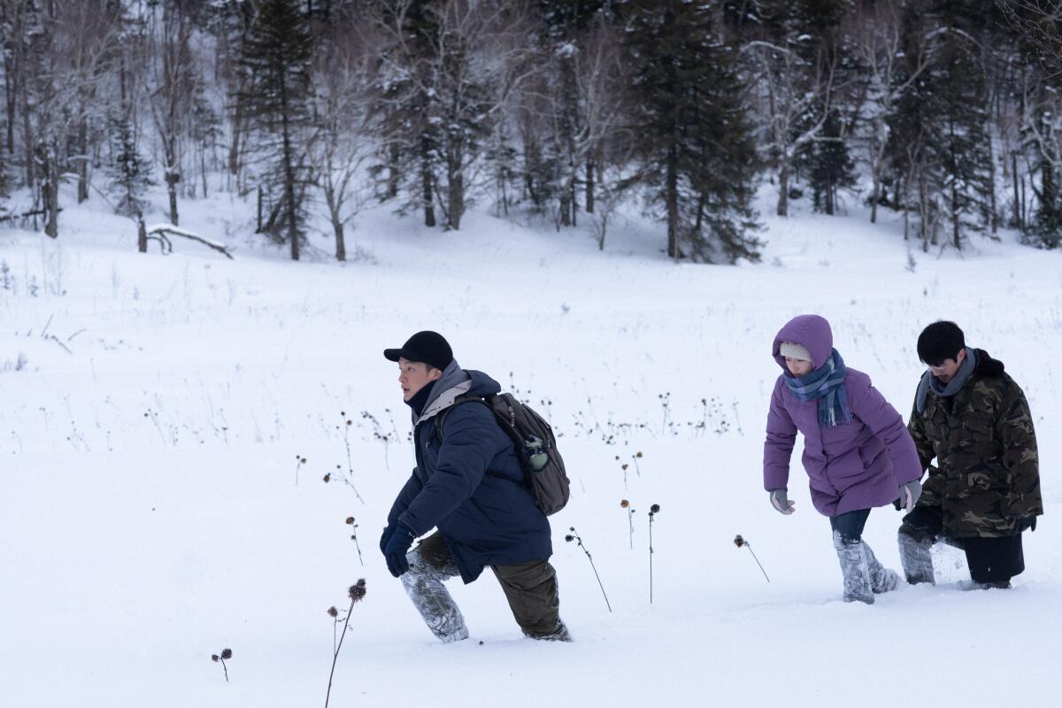 Three people walk in the snow.