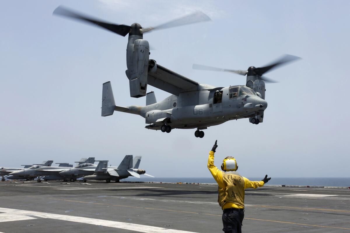 U.S. Navy sailor signals an MV-22 Osprey to land on the flight deck of the USS Abraham Lincoln in the Arabian Sea.