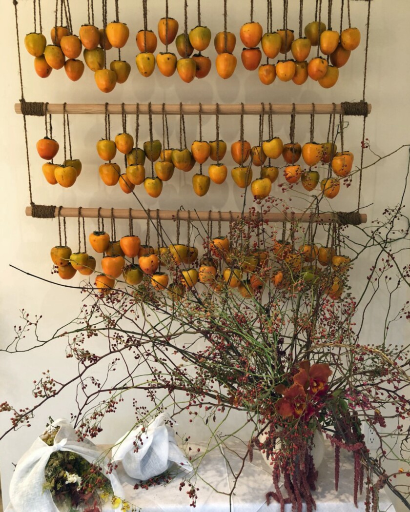 A display of flowers and hanging persimmons.