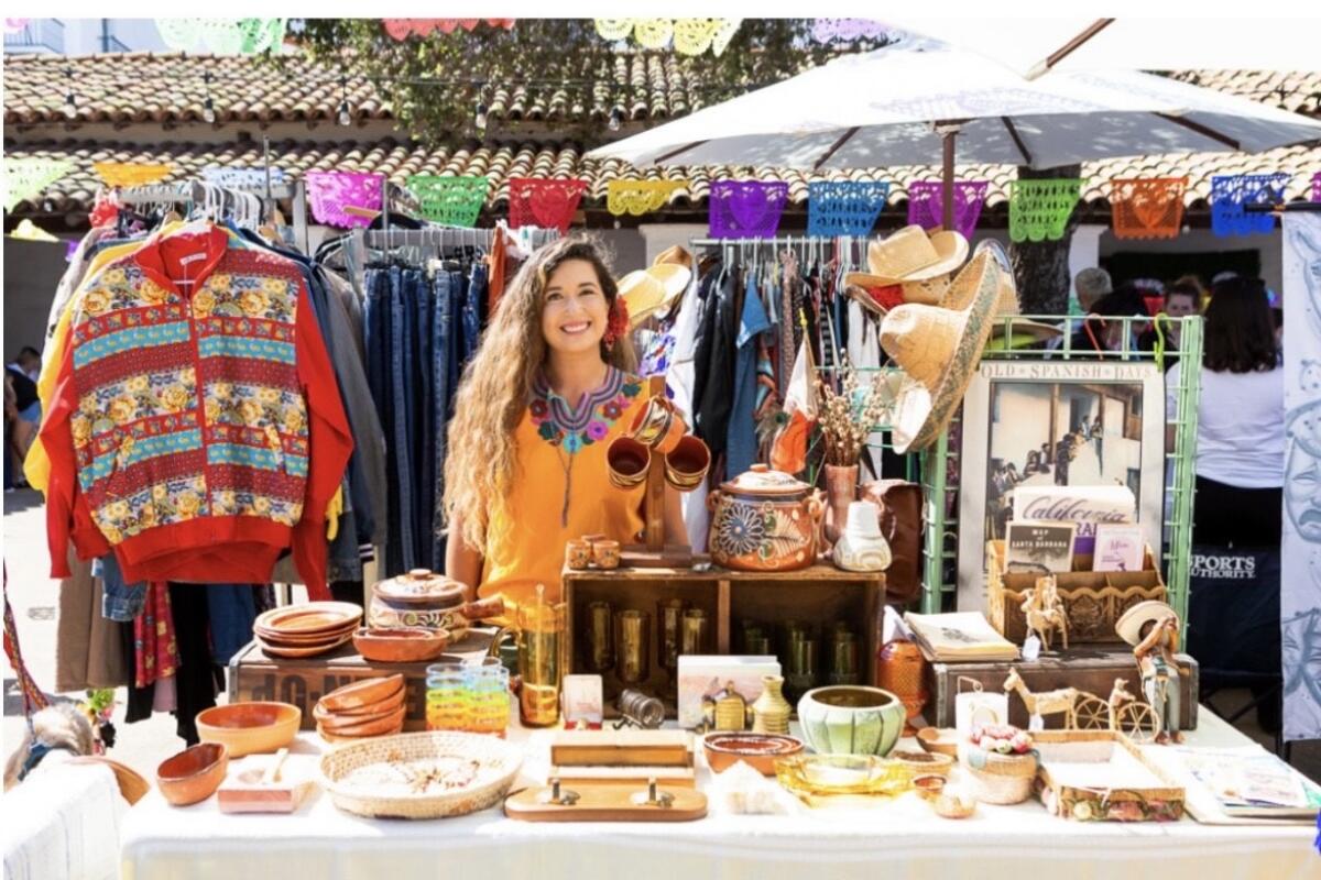 A woman behind a table selling goods outside 