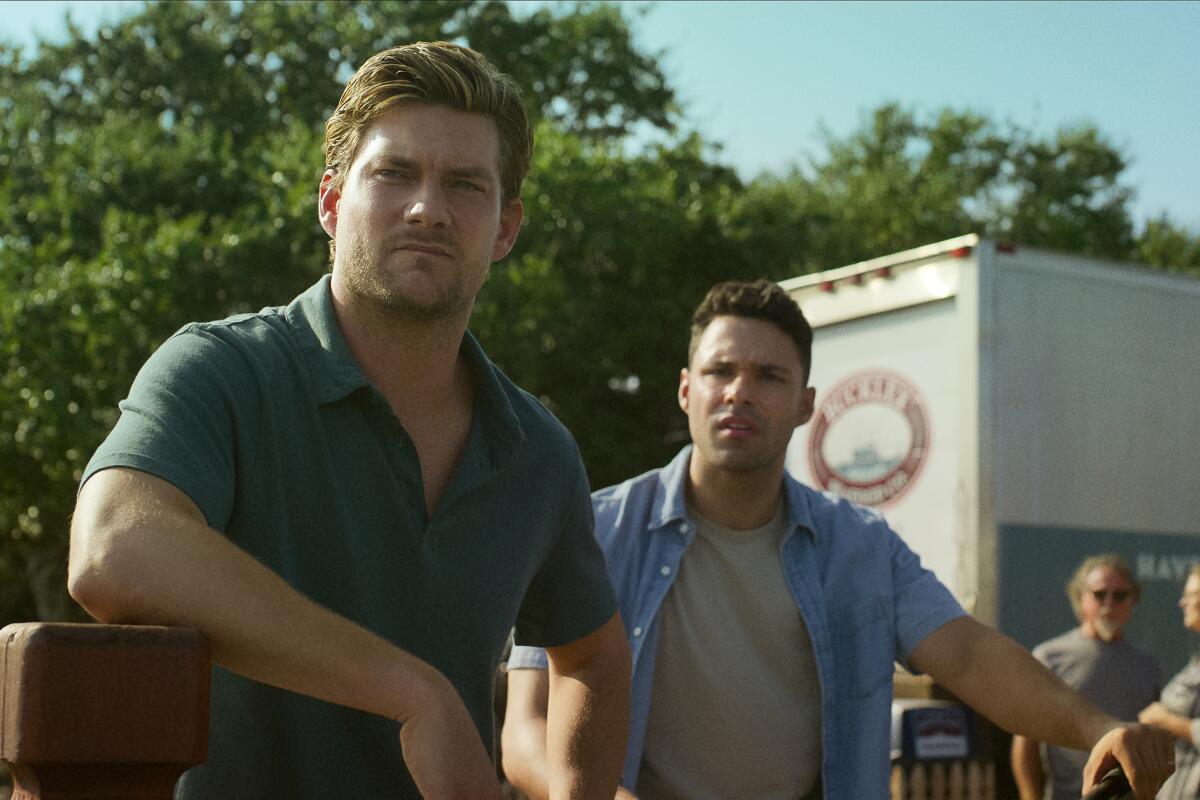 Two men standing with a box truck in the background.
