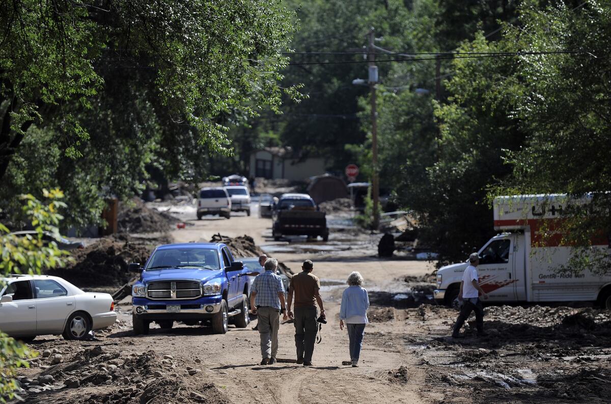 People walk through a severely flooded neighborhood in Lyons, Colo. Residents displaced by last week's flooding in the Colorado canyon town were allowed past National Guard roadblocks Thursday.