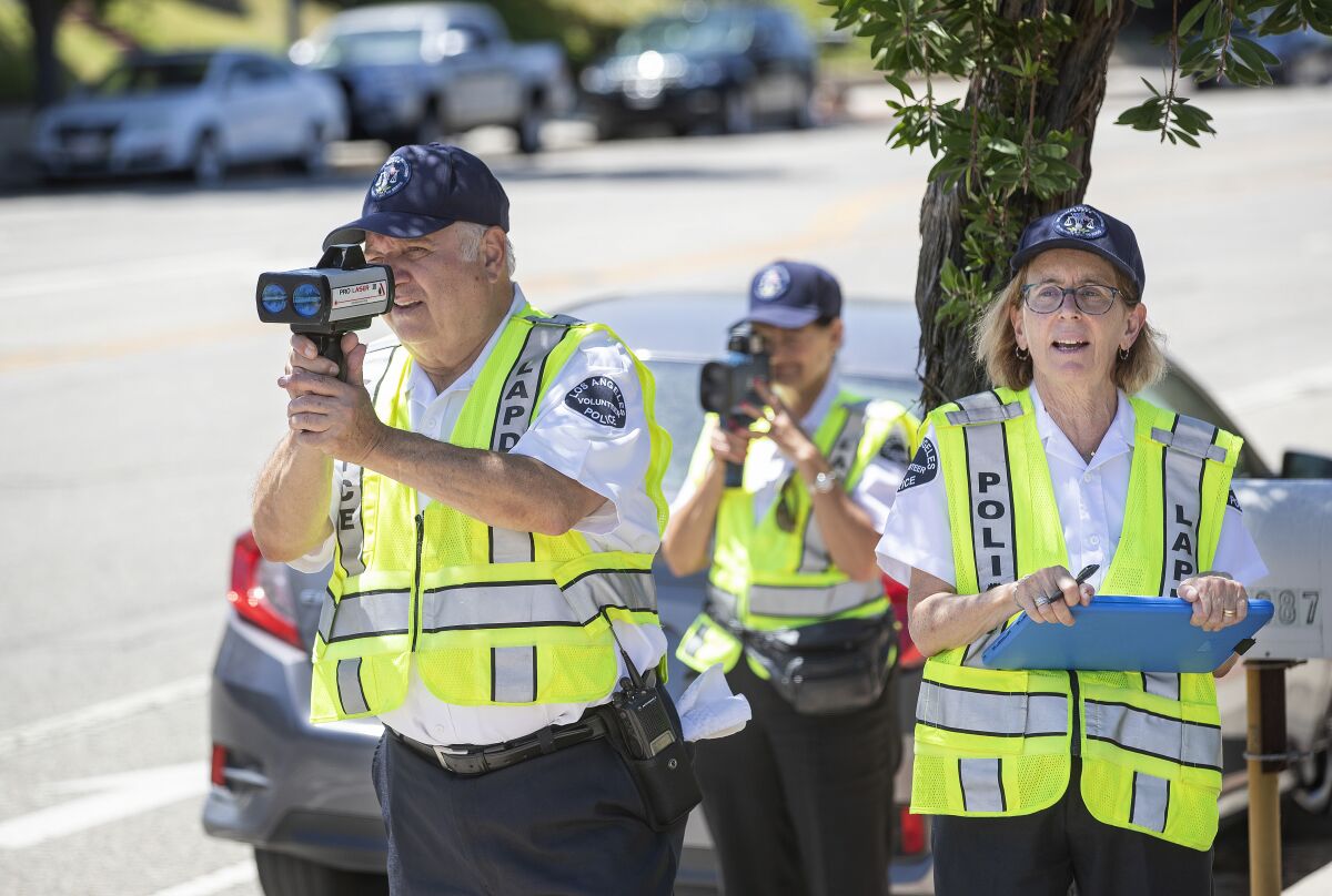Two people hold speed radar guns up to their faces while a third holds a clipboard