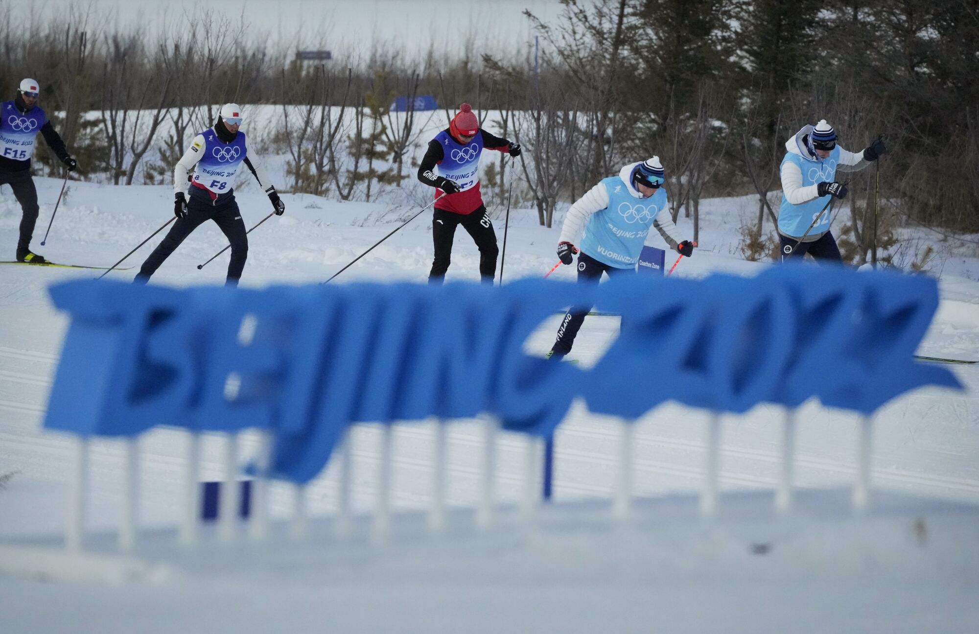 Cross-country skiers practice behind a "Beijing 2022" sign during a training session 