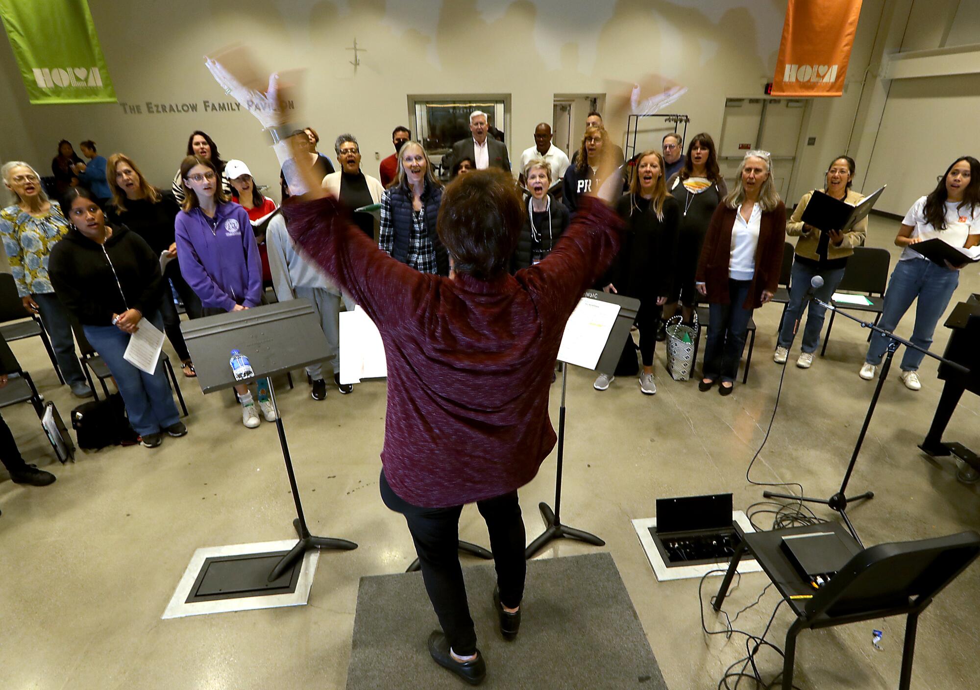 Lydia Saxton conducts the Heart of L.A. choir during a rehearsal at Lafayette Park in Los Angeles. 