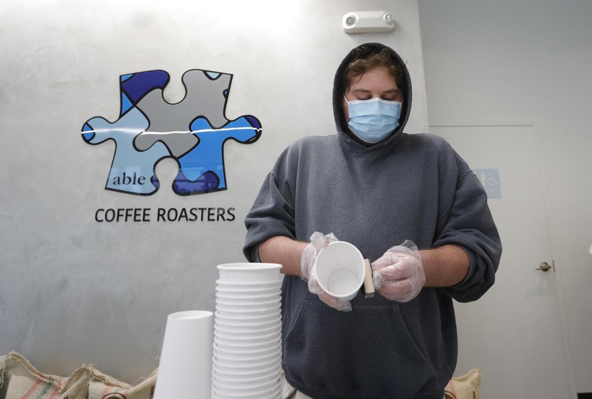 An Able Coffee employee stamps the company logo on coffee cups at the Huntington Beach location.