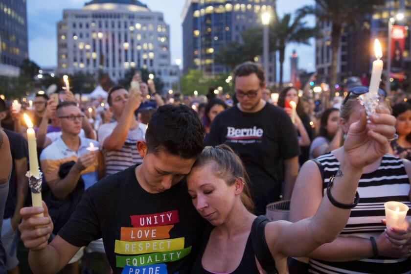 Jennifer, right, and Mary Ware hold up candles during a vigil downtown for the victims of a mass shooting at the Pulse nightclub Monday, June 13, 2016, in Orlando, Fla. (AP Photo/David Goldman)