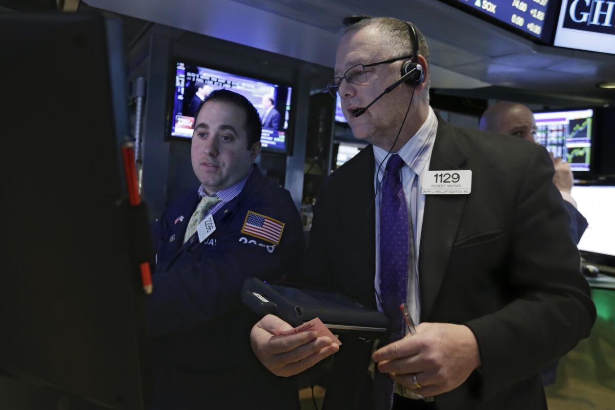 Trader Robert Moran, right, works on the floor of the New York Stock Exchange where stocks are opening slightly lower a day after the market notched its best performance in five weeks.