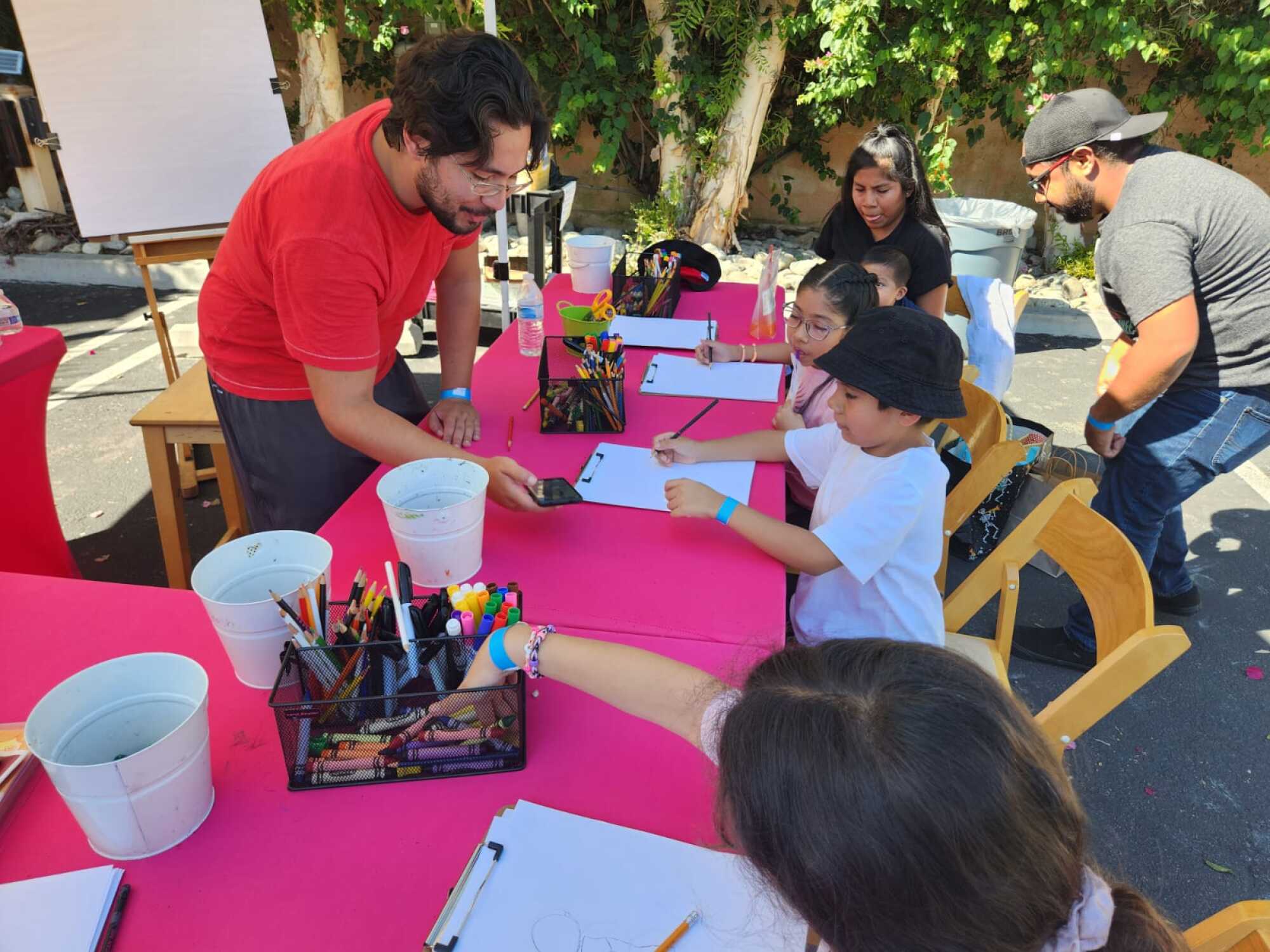 A man instructs children seated at a table