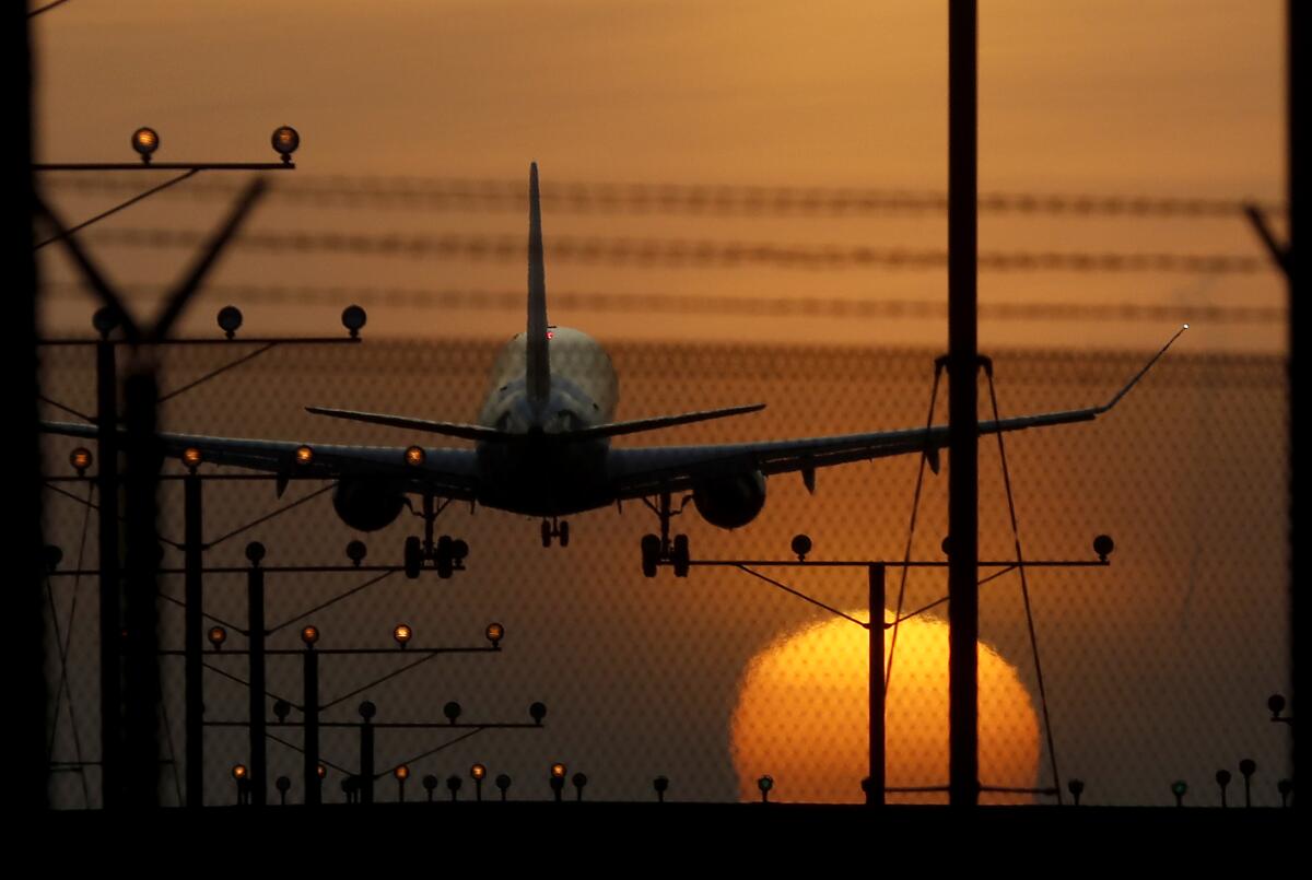 A passenger jet approaching a runway at sunset