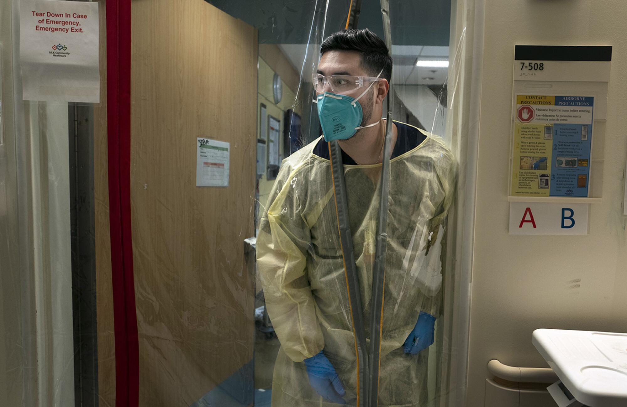 Nurse Fernando Fernandez looks through a plastic covering at the hospital.