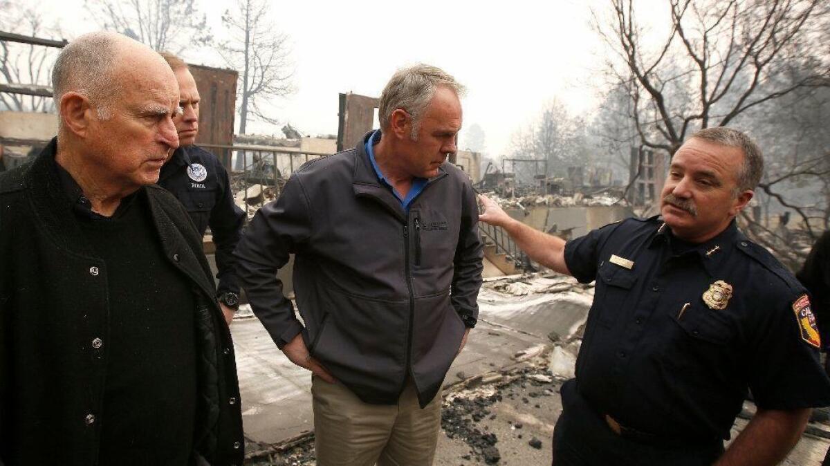 Gov. Jerry Brown and U.S. Interior Secretary Ryan Zinke tour a scorched area of Paradise, Calif., on Nov. 14, 2018.