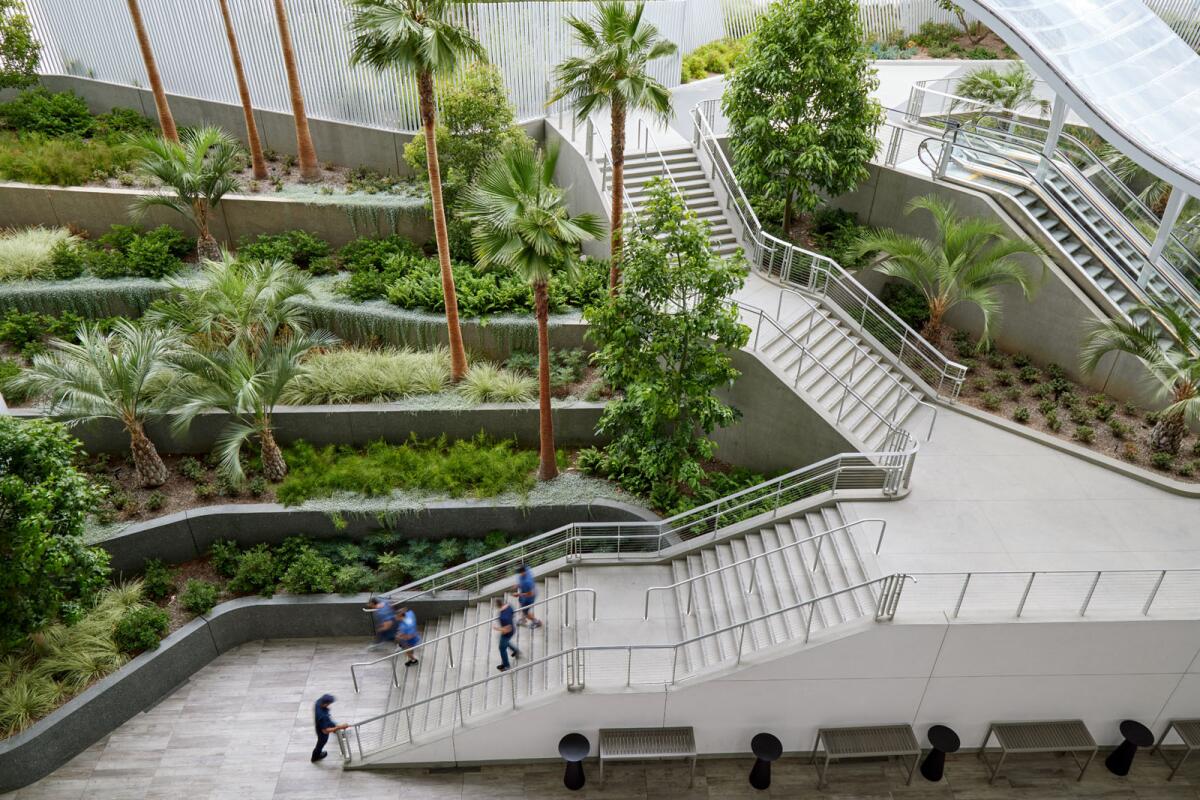 An overhead view shows a staircase and an escalator descending into a terraced garden.