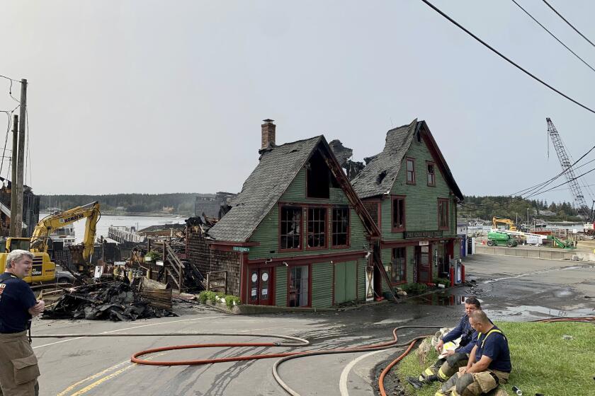 Firefighters rest on Thursday, Sept. 28, 2023, after battling a fire that destroyed the Port Clyde General Store and other waterfront businesses overnight, in Port Clyde, Maine. The fire destroyed an art gallery with several paintings by Jamie Wyeth and an illustration by his grandfather, N.C. Wyeth., the building's owner said Friday. (Jules Walkup/The Bangor Daily News via AP)