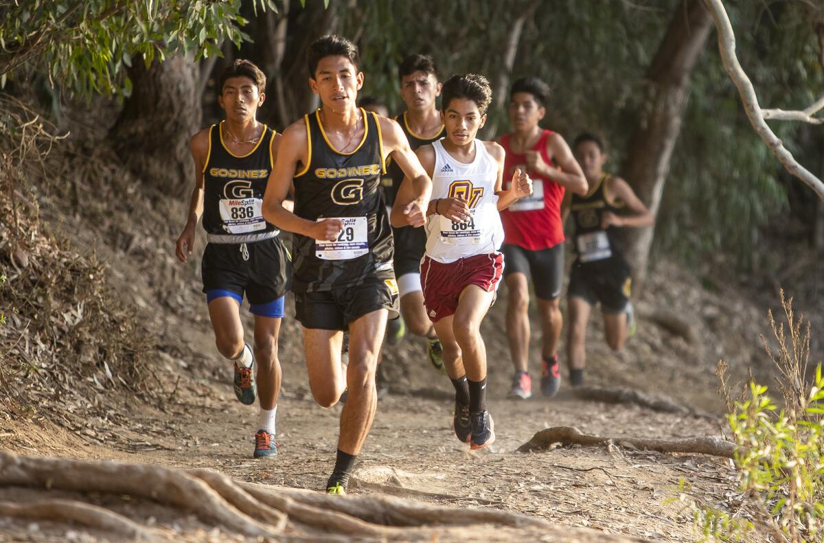 Godinez's Juan Avendano, center, Adalbert De Jesus, left, and Ocean View's Diego Gonzalez run in a technical section of the trail during the Golden West League boys' finals at Central Park in Huntington Beach on Wednesday.