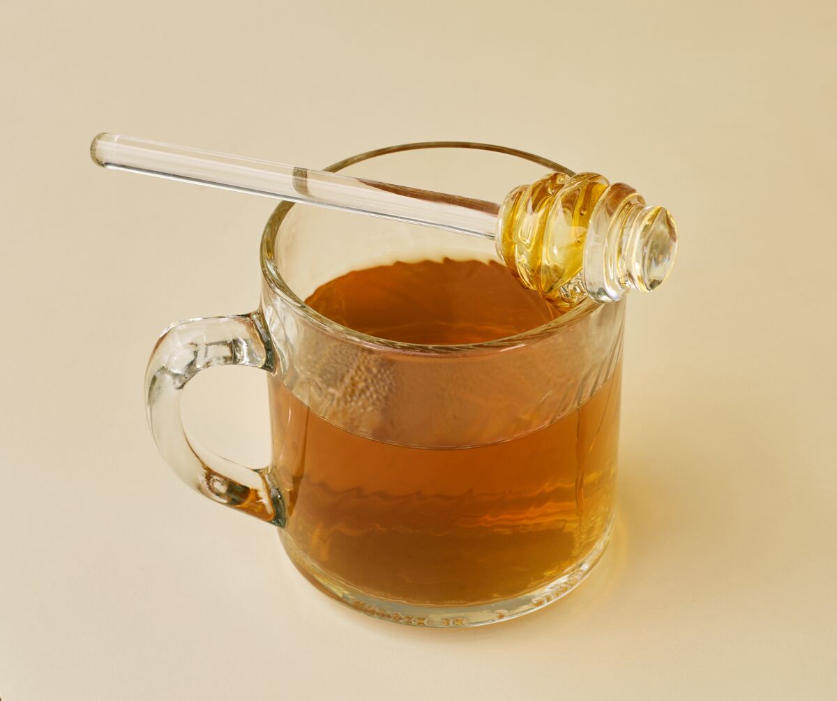 A hot toddy, with a honey dipper resting on the top.