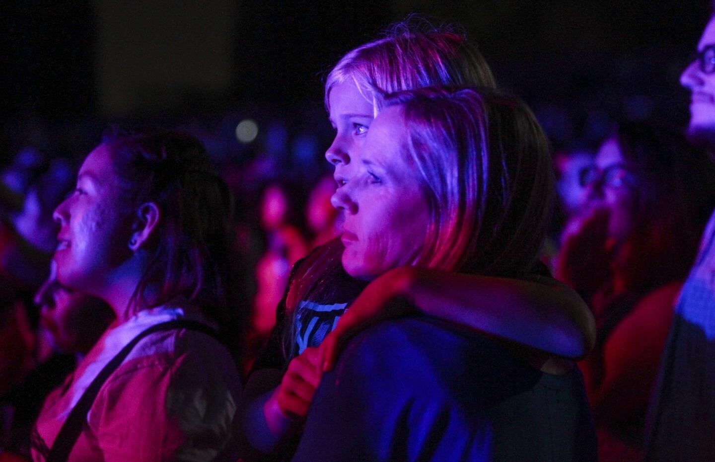 A woman holds a child as they watch Nick Jonas perform.