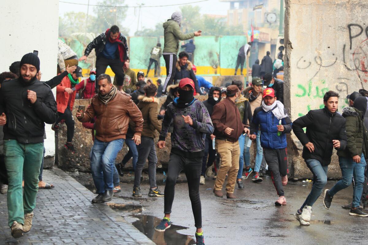 Anti-government protesters run during clashes with Iraqi security forces in Baghdad on Jan. 25, 2020. Security forces set fire to anti-government protest tents in southern Iraq early Saturday and reopened key public squares in Baghdad that had been occupied by demonstrators for months.