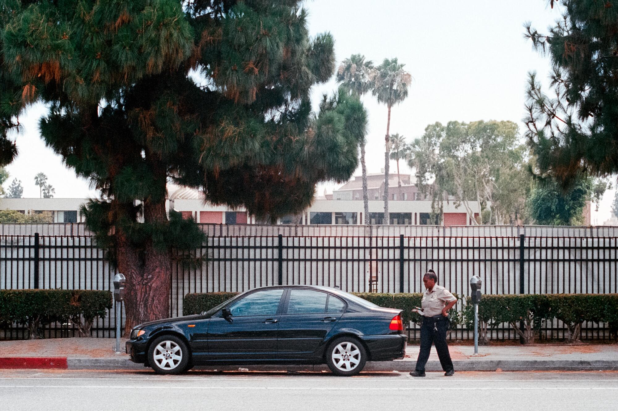 An officer walks by a parked car.