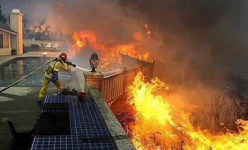 Santa Clara firefighter Jason Falarski battles to save a house in Poway in October. Falarski said of this moment: "The main thing going through my mind is, 'I don't want to lose this house.' "