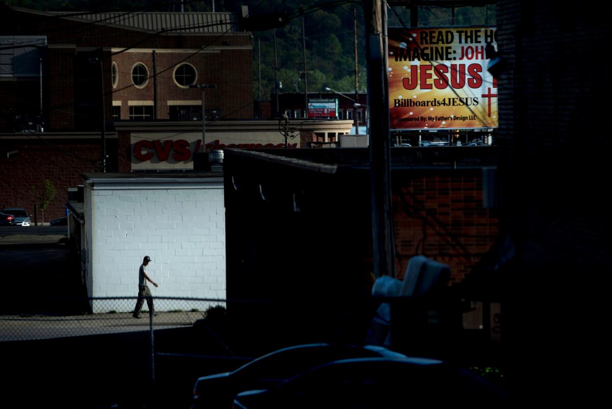 A man walks down an alley near a billboard for Jesus 