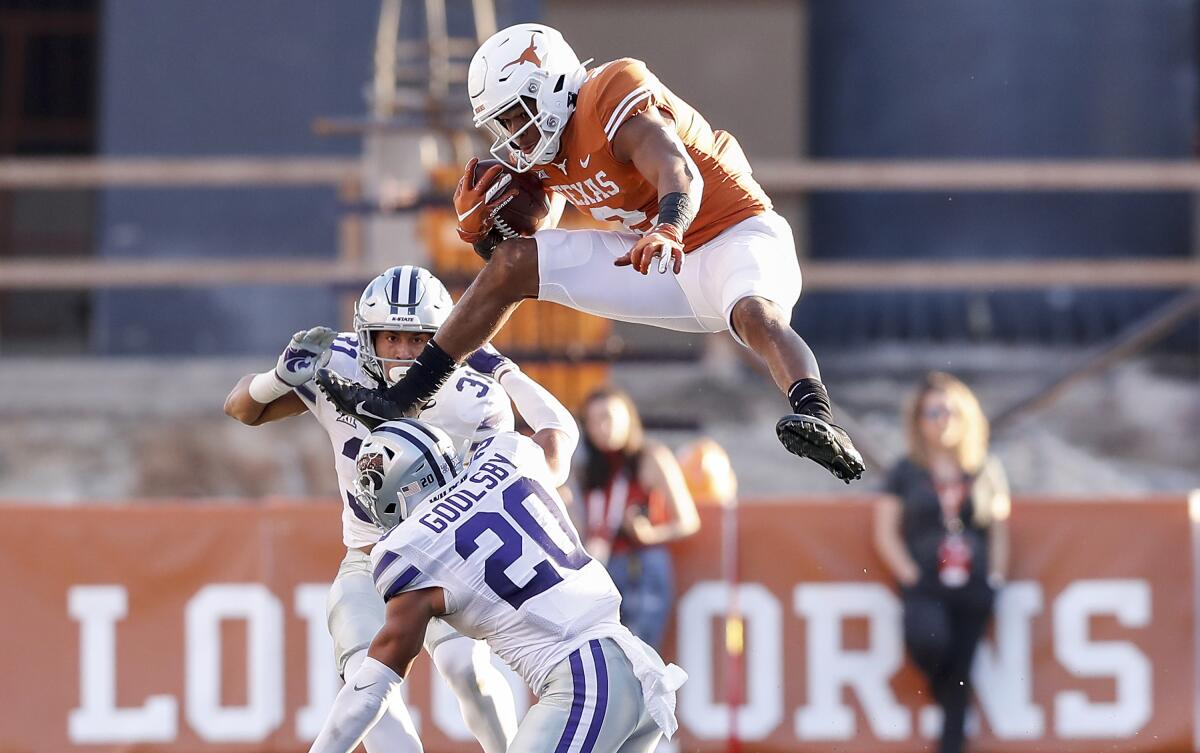 Texas quarterback Roschon Johnson hurdles Kansas State defensive back Denzel Goolsby.