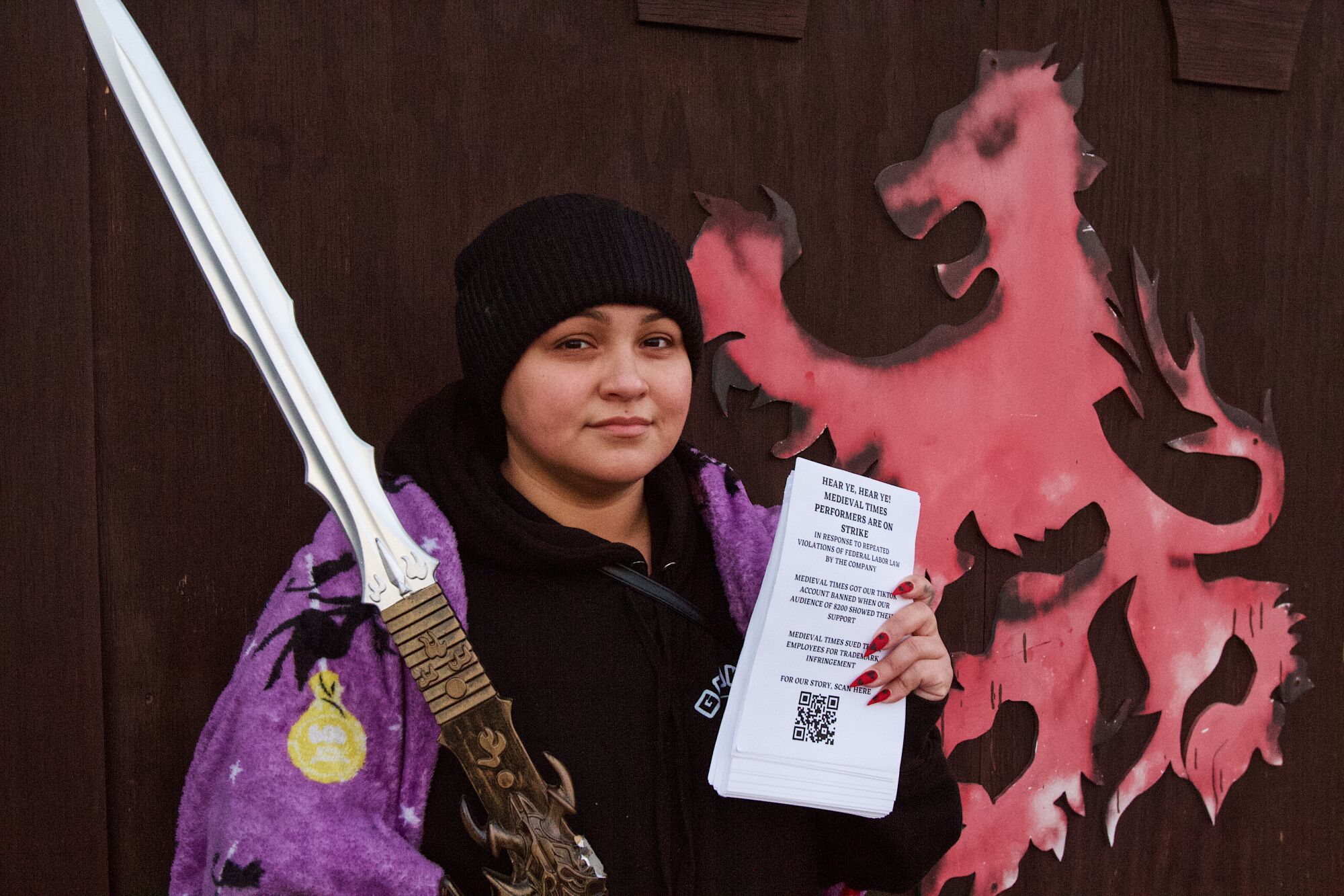 Katherine Calderon holds a fake sword in one hand and a small stack of strike fliers in the other