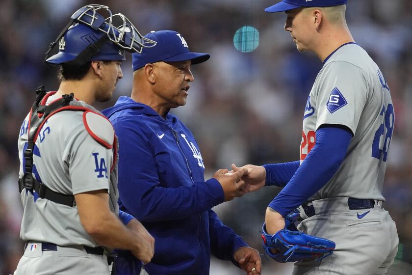 Los Angeles Dodgers manager Dave Roberts, center, takes the ball from starting pitcher Bobby Miller, right, as he is pulled from the mound while catcher Austin Barnes looks on in the seventh inning of a baseball game against the Colorado Rockies Wednesday, June 19, 2024, in Denver. (AP Photo/David Zalubowski)