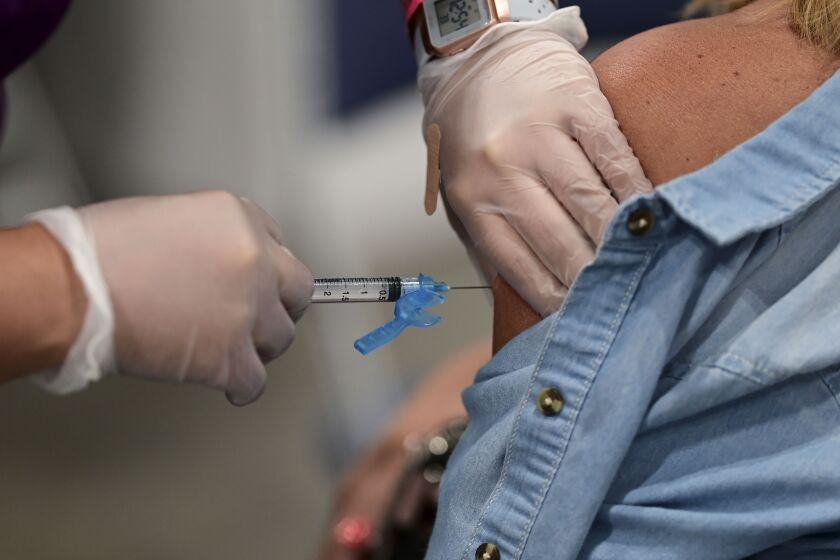 A health worker applies a Johnson and Johnson COVID-19 vaccine during a mass vaccination event carried out by the Department of Health and the Voces nonprofit organization, at the Miramar Convention Center in San Juan, Puerto Rico, Wednesday, March 31, 2021. (AP Photo/Carlos Giusti)