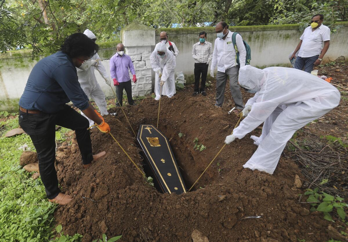 People lower the coffin of a man who died of COVID-19 at a cemetery in India.