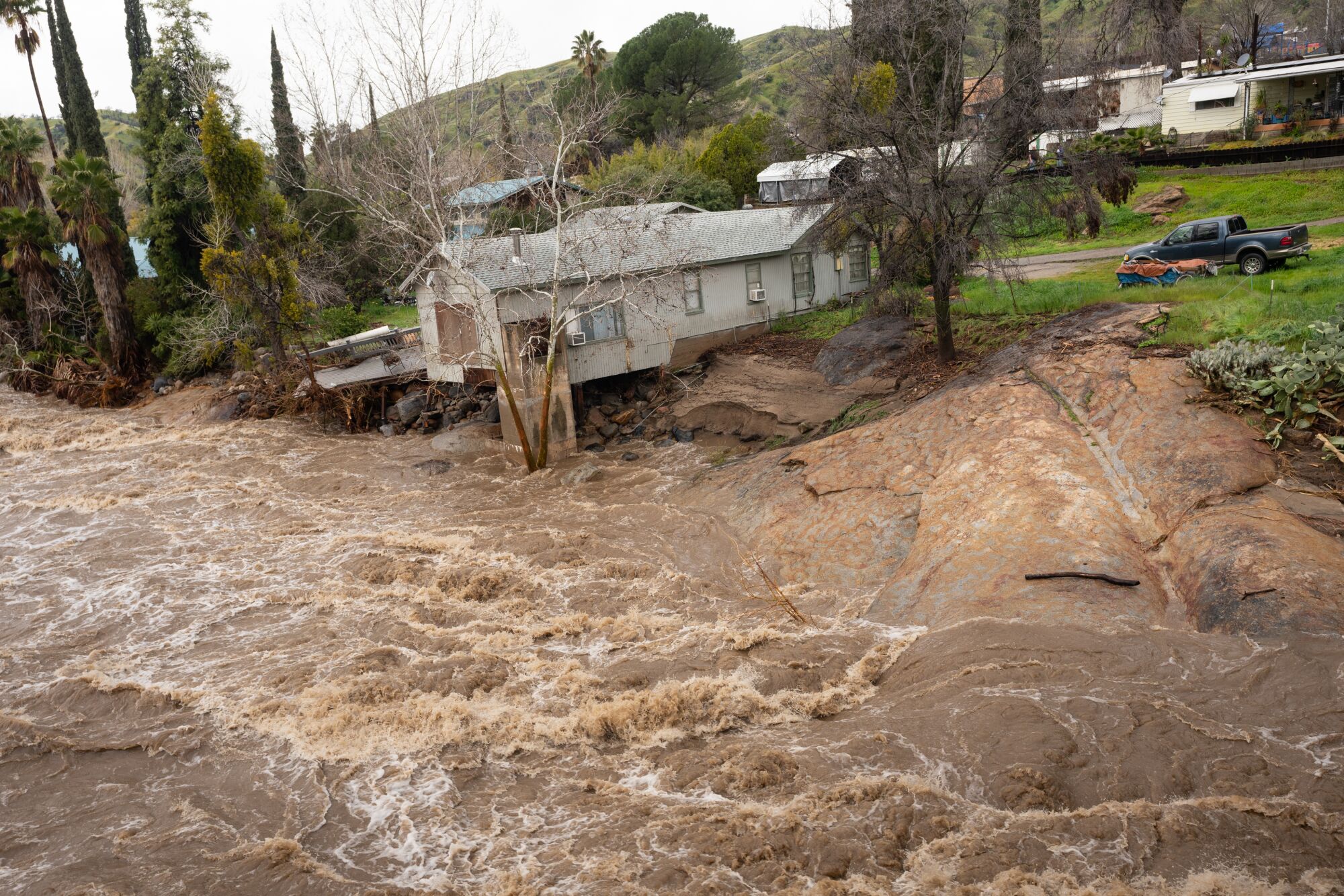 A raging river carries away the foundations of a house. 