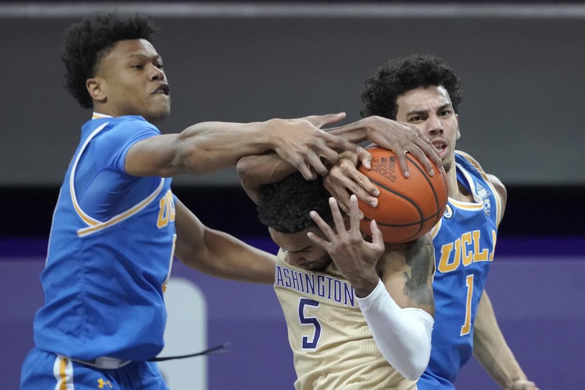 UCLA's Jaylen Clark, left, and Jules Bernard, right, battle Washington's Jamal Bey for a rebound Feb. 13, 2021.