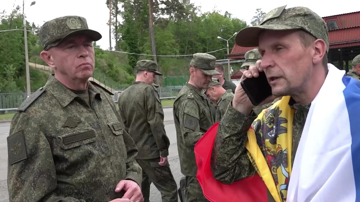 A serviceman wrapped in a flag speaks on the phone.