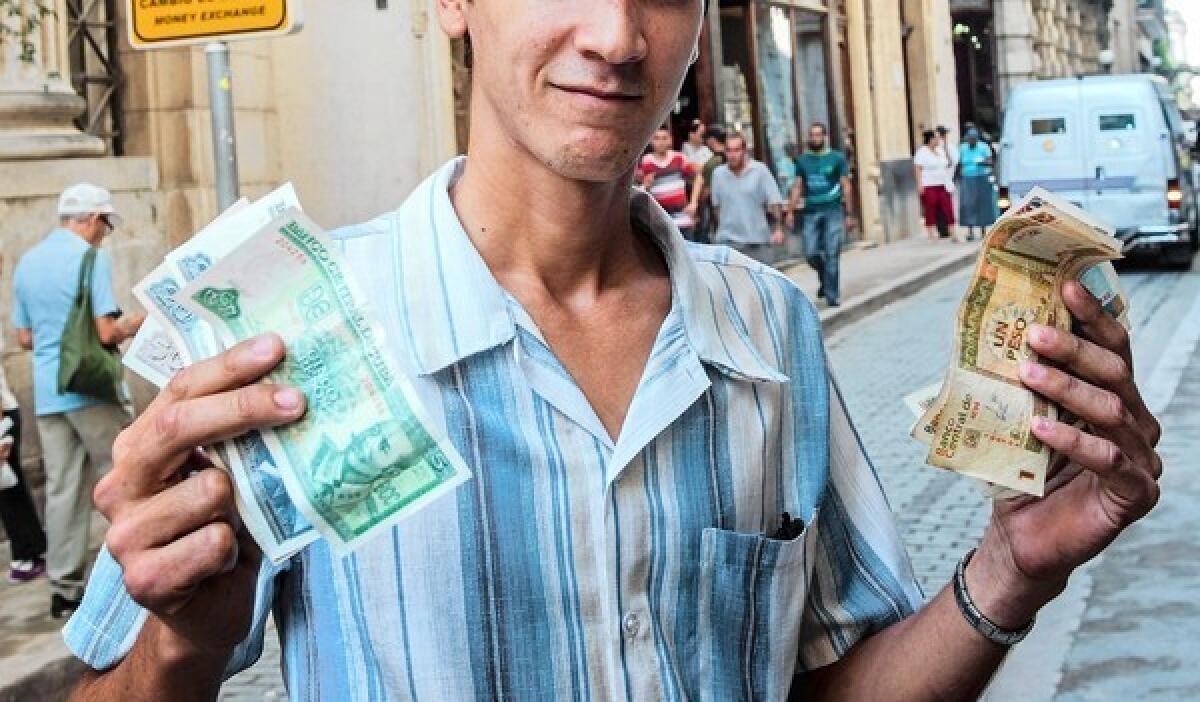 A Cuban displays Cuban pesos, left, and the more valuable convertible pesos Tuesday in Havana. Raul Castro's government announced that the dual-currency system will be changed.