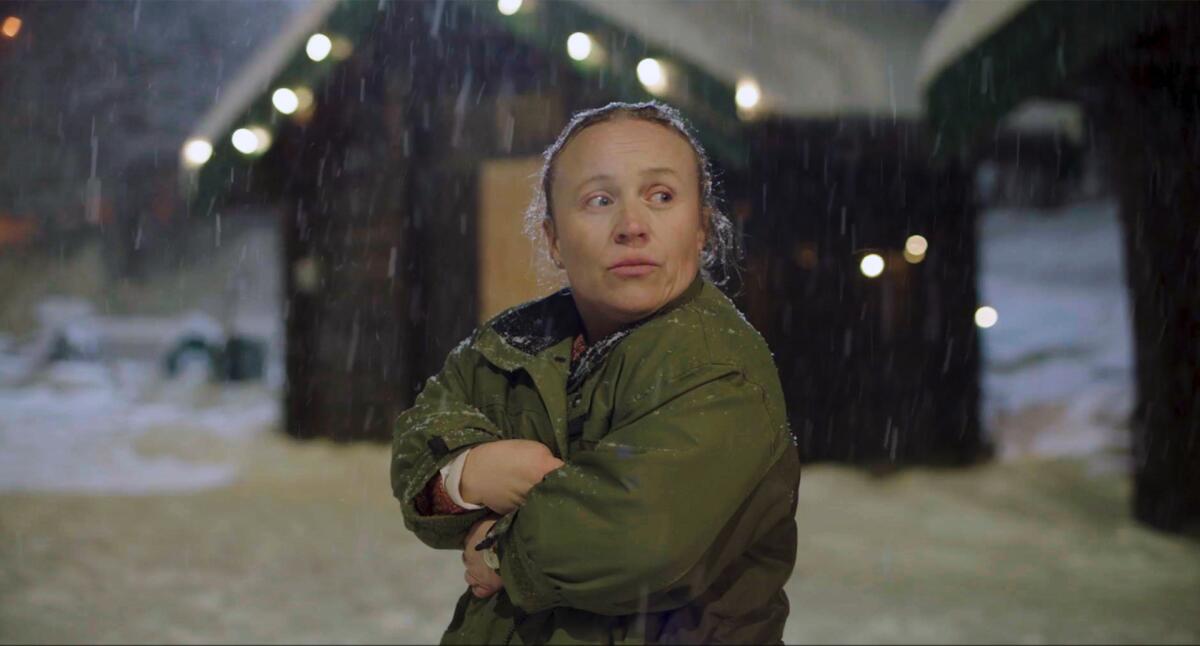 A woman in a coat clutches herself from the cold in a scene from "Night Ride."