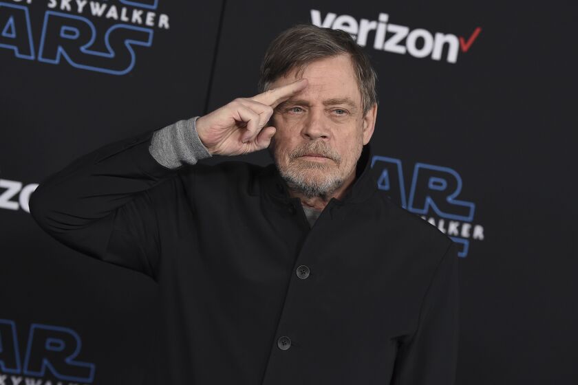 Man, Mark Hamil, saluting, wearing black button-up shirt, at Star Wars event in Los Angeles