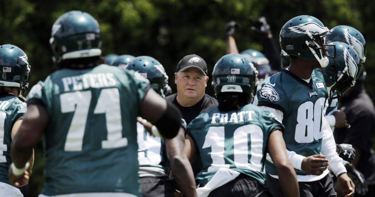 All eyes are on Coach Chip Kelly, center, as the Eagles open training camp with many new faces after Kelly overhauled the roster.
