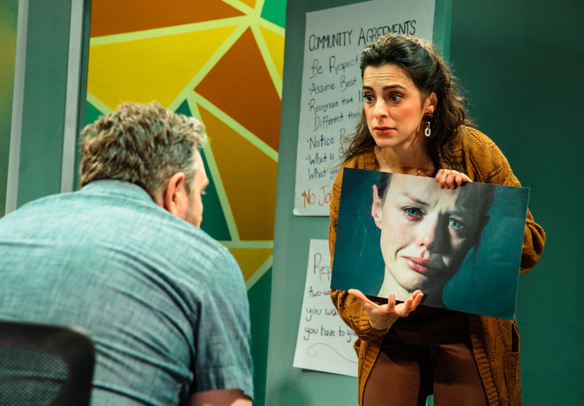 A woman holds up a picture of a crying woman to a man