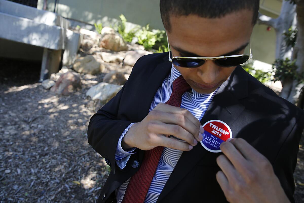 Ian McIlvoy, a Westmont College student who supports Donald Trump, affixes a Trump campaign sticker to his lapel.