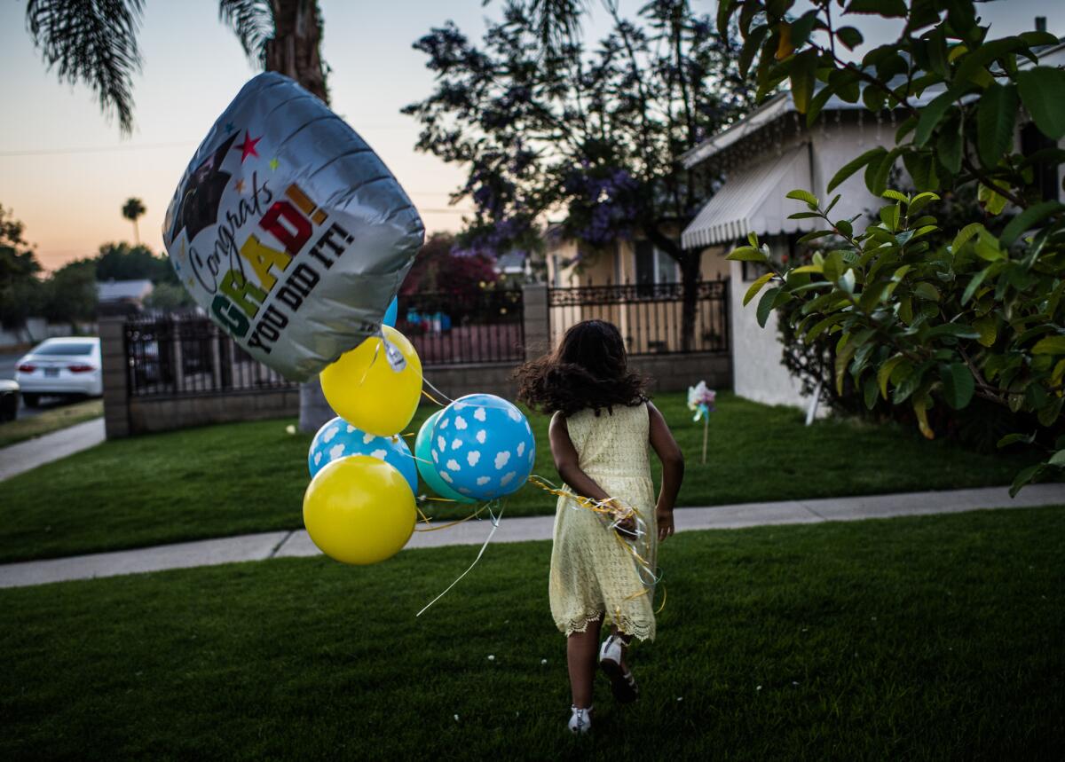 After her kindergarten graduation, Marley runs with balloons outside her home in Arleta.