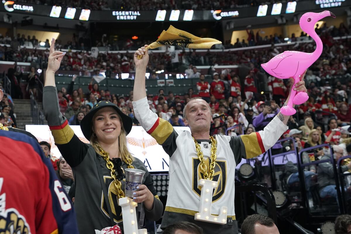 two people in Golden Knights hockey jerseys cheer, one holding up a plastic flamingo