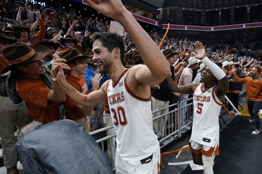 Texas forward Brock Cunningham (30) and guard Marcus Carr (5) celebrate with fans after the team's win over Creighton in an NCAA college basketball game in Austin, Texas, Thursday, Dec. 1, 2022. (AP Photo/Eric Gay)