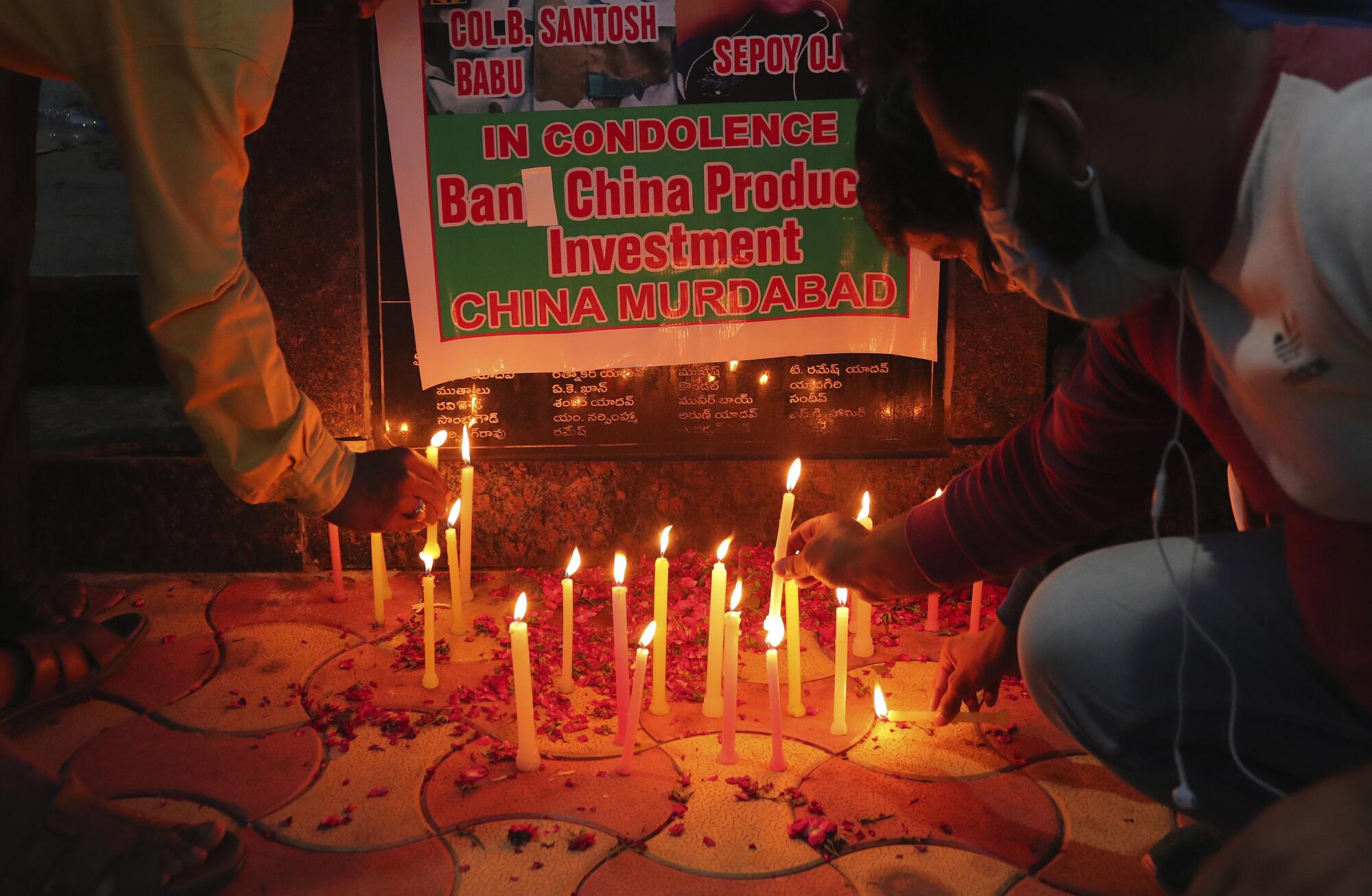 People light candles near a poster that calls for a ban on China products and investment
