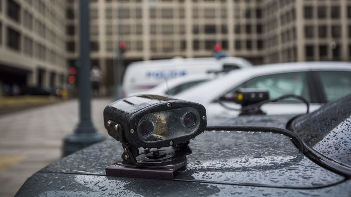An automated license plate reader mounted to the back of an unmarked police car.